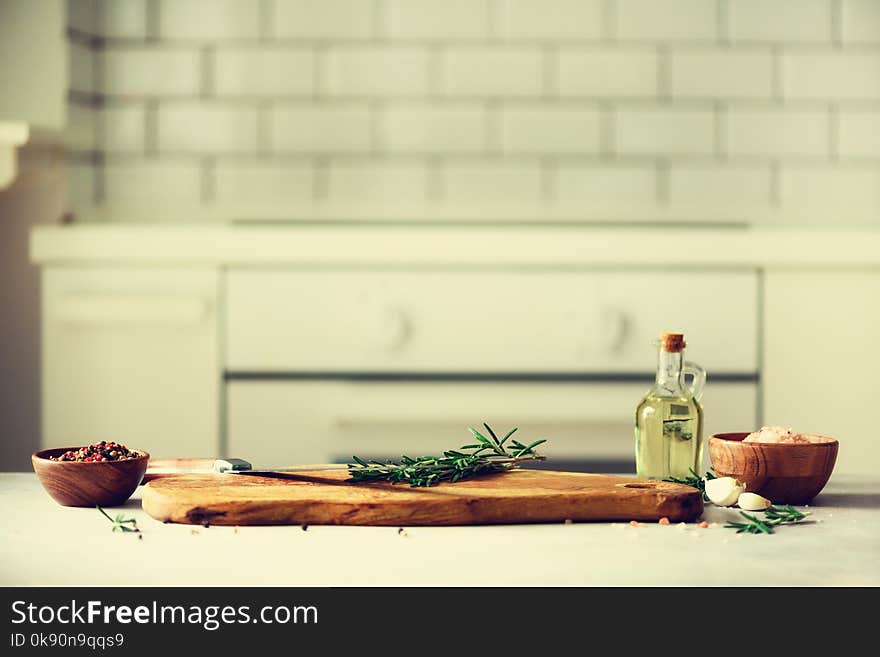 Food cooking ingredients on white kitchen design interior background with rustic wooden chopping board in center, copy