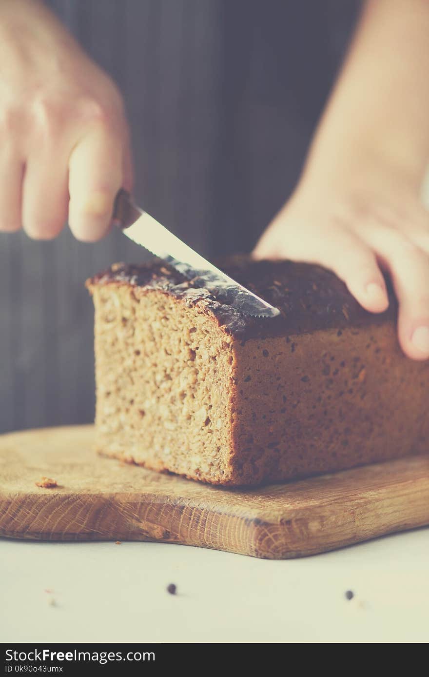 Woman hands slicing freshly backed bread. Handmade brown loaf of bread, bakery concept, homemade food, healthy eating. Copy space.