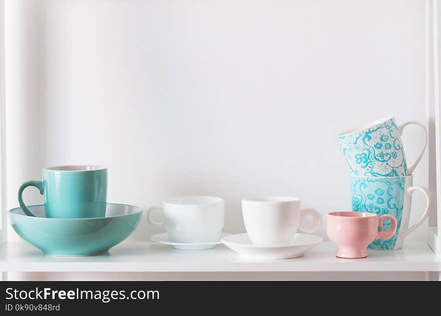 Cups on white shelf on white background