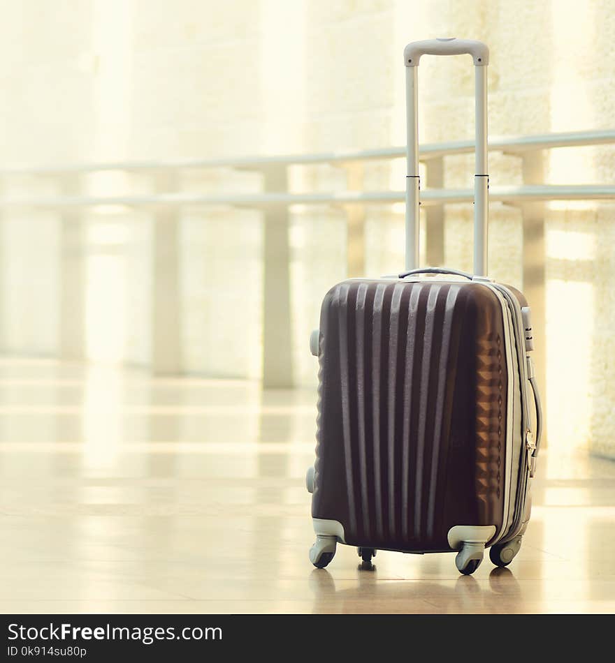 Packed travel suitcase, airport. Summer holiday and vacation concept. Traveler baggage, brown luggage in empty hall