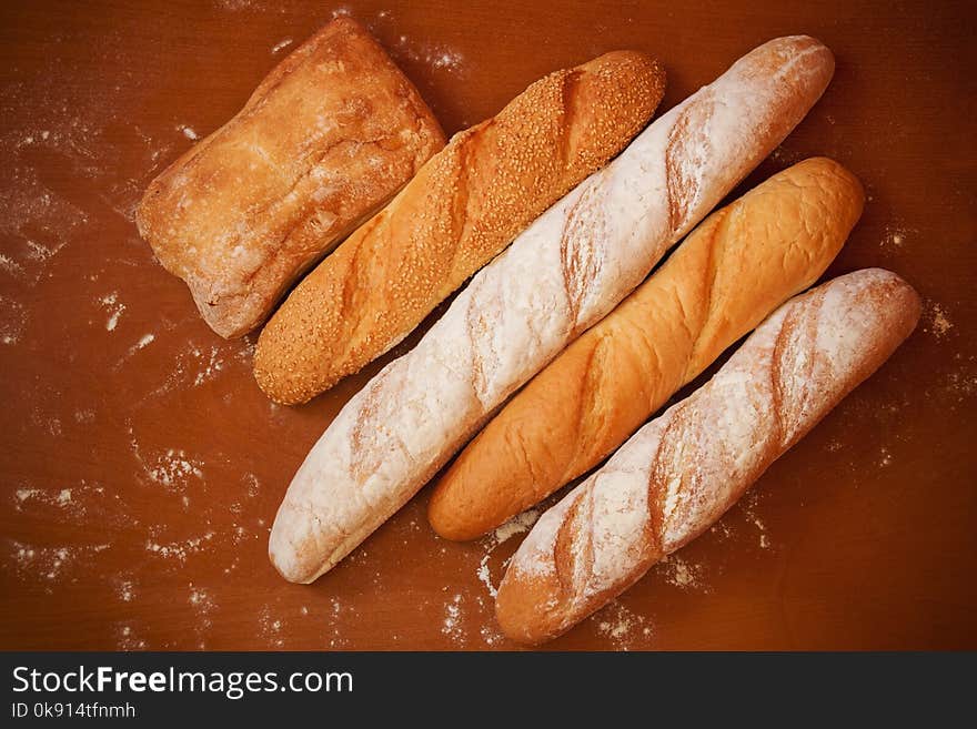 Assortment of baked bread on wooden background. Top view.