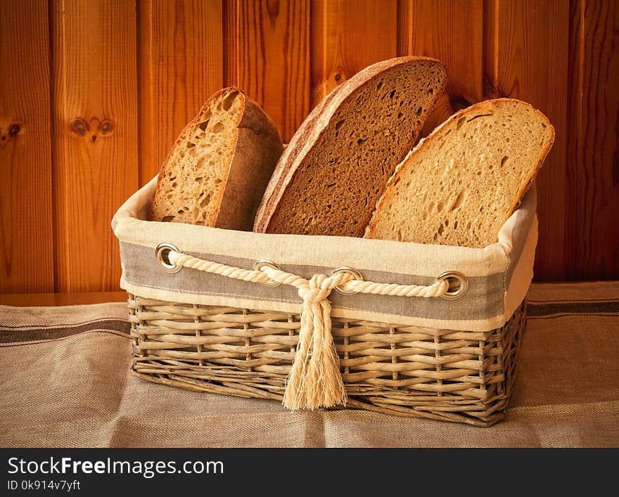 Rustic wicker basket with fresh rye bread on wooden background. Vintage style. Rustic wicker basket with fresh rye bread on wooden background. Vintage style.