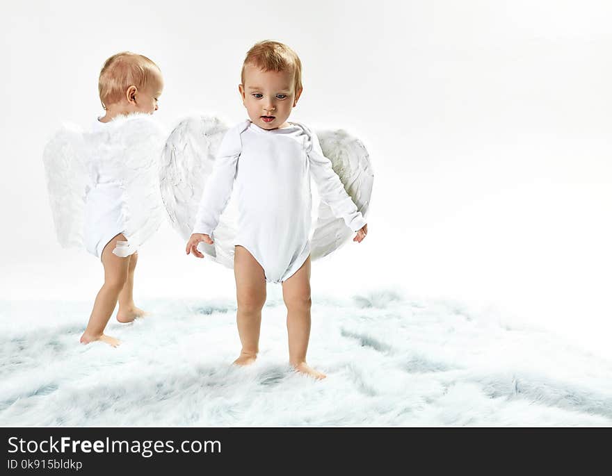 Two cute baby angels walking on the soft carpet