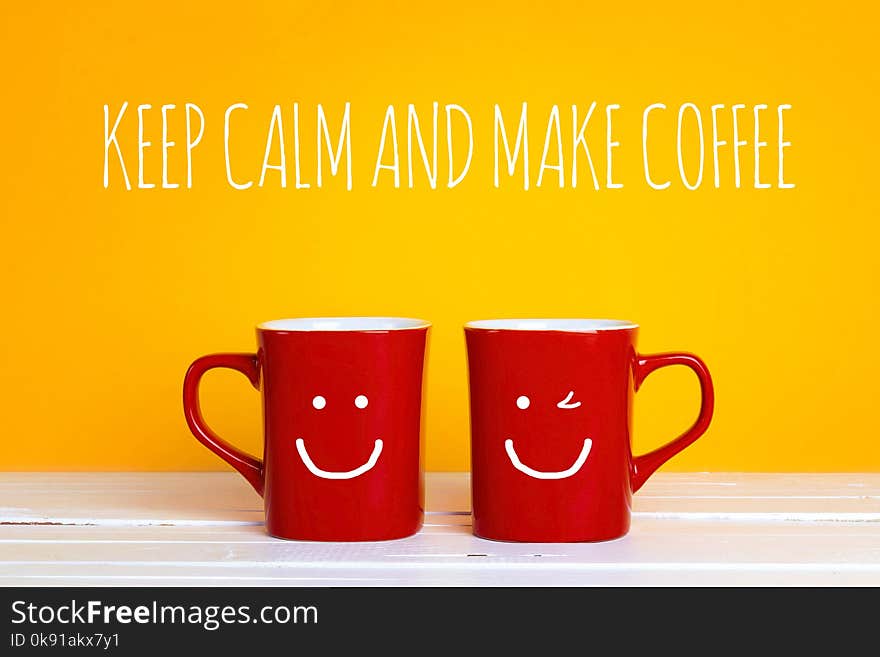 Two red coffee mugs with a smiling faces on a yellow background with the phrase Keep calm and make coffee. Happy coffee mugs.