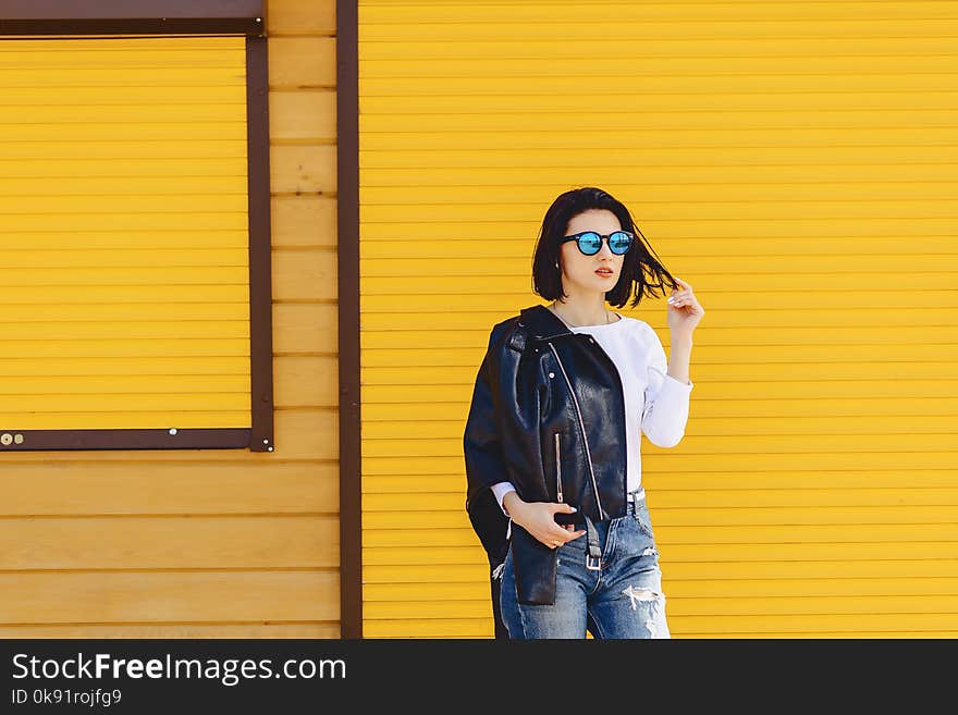 Beautiful girl sunglasses on bright yellow background outside