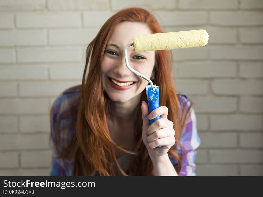 Photo of red-haired girl in a bright t-shirt that holds brushes for drawing