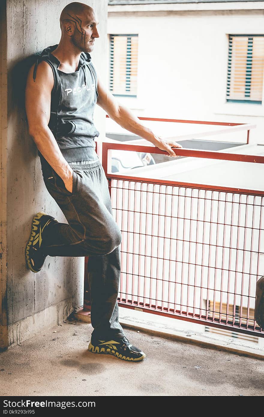 Man in Black Tank Top Leaning on Wall