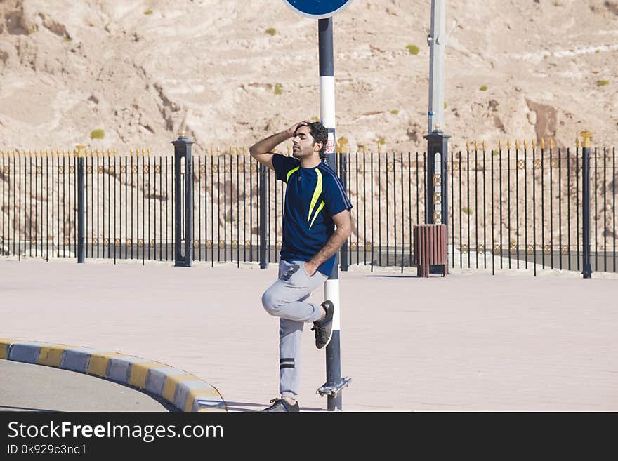 Man Wearing Blue Crew-neck Shirt Leaning on Street Post