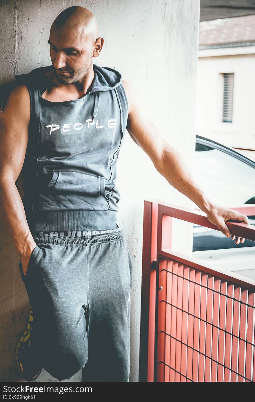 Photography of Man in Gray Sleeveless Top Standing Near Gray Concrete Wall