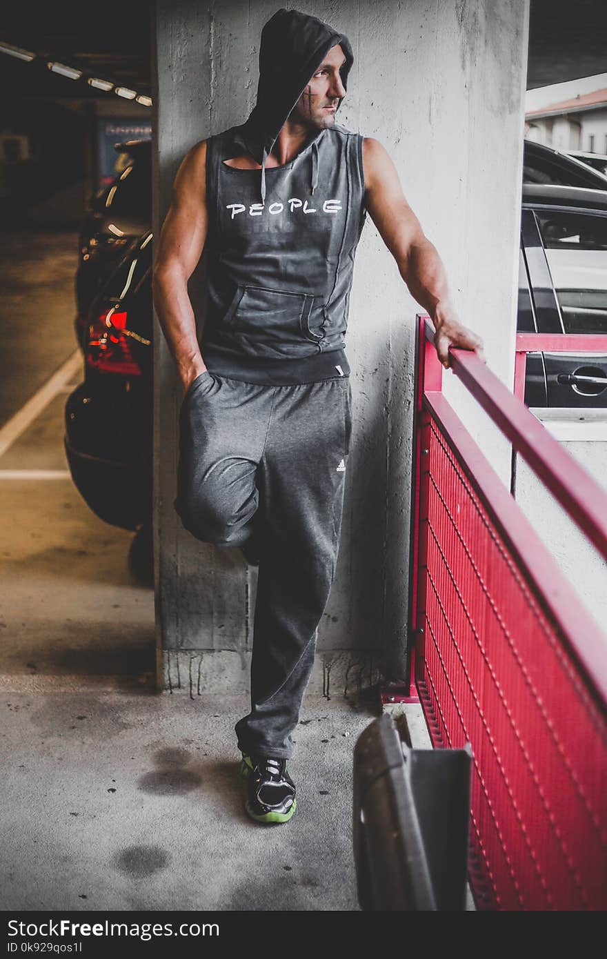 Man Wearing Black Tracksuit Standing Beside Red Metal Fence