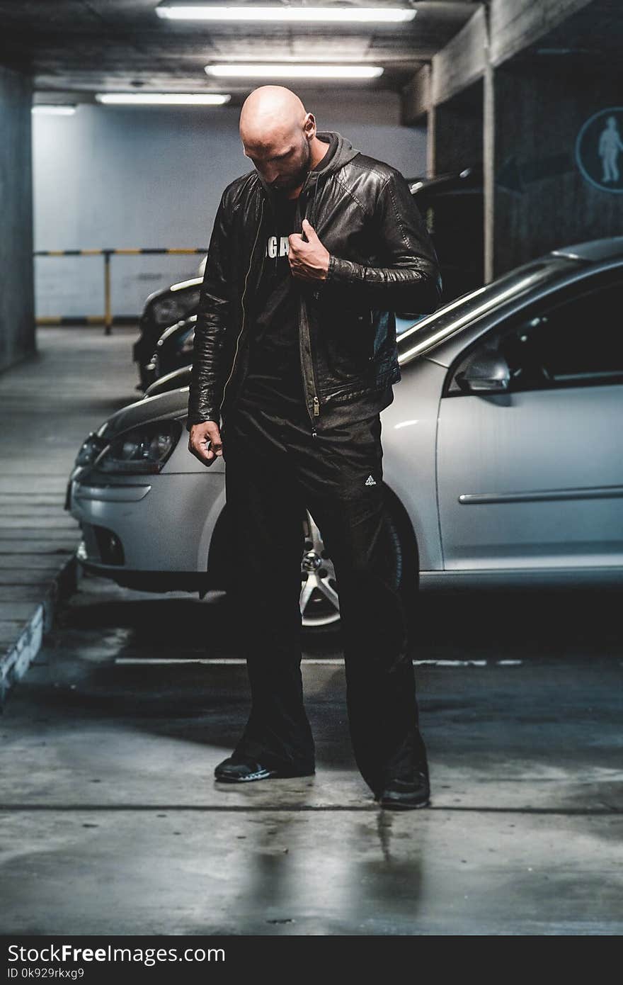 Man in Black Leather Jacket Standing in Front of Gray Car