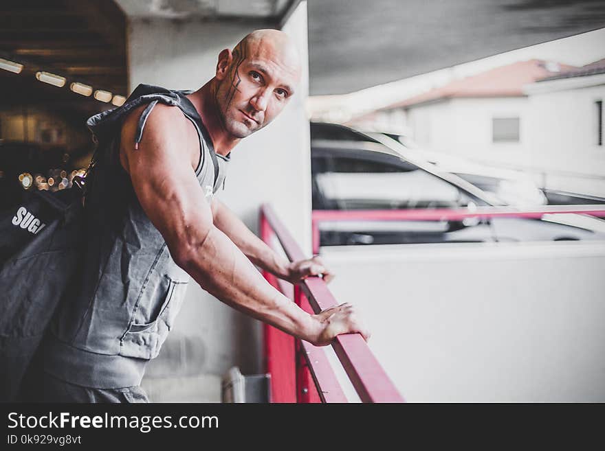 Man Wearing Gray Apron Placing His Hands on Red Metal Handrail