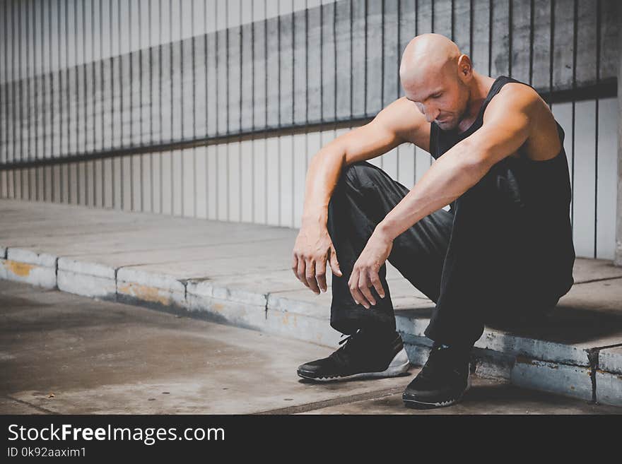 Man Sitting on Sidewalk