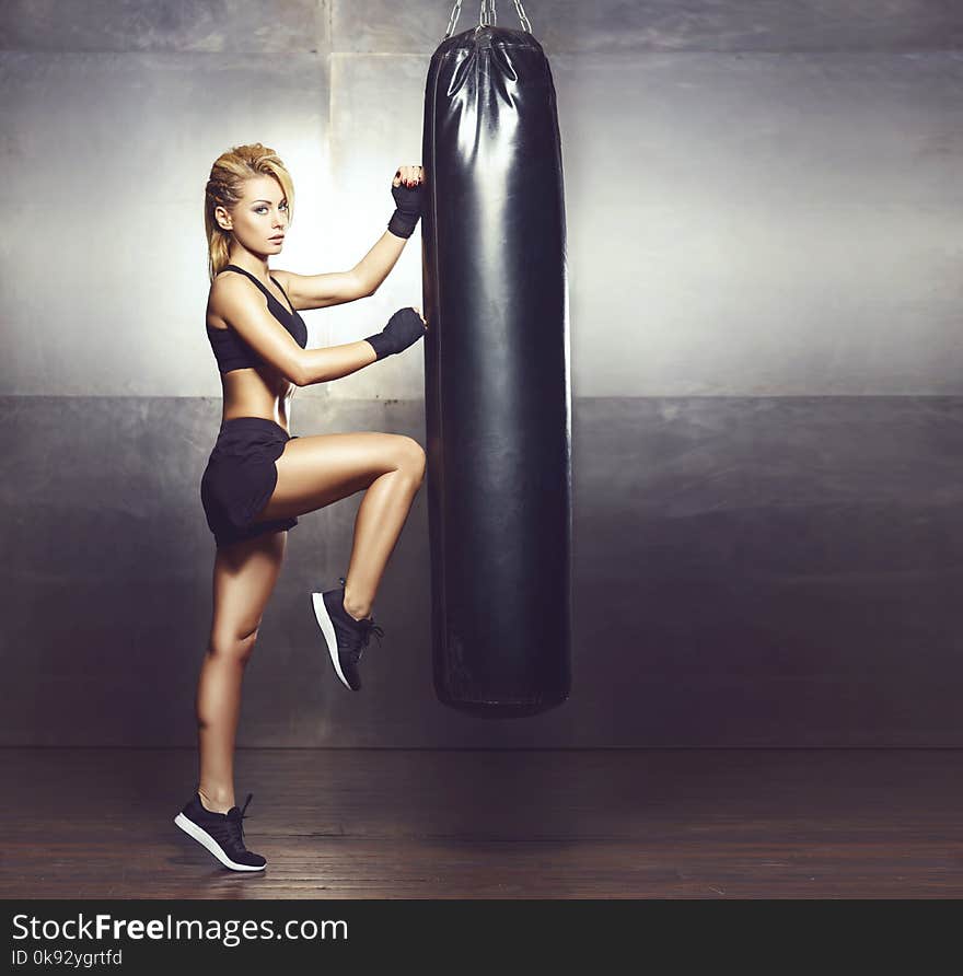 Fit and sporty young girl having a kickboxing training. Underground gym. Health, sport, fitness concept.