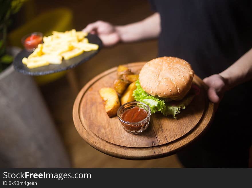 Waiter holds fresh hot burger with potatoes in restaurant. Waiter holds fresh hot burger with potatoes in restaurant