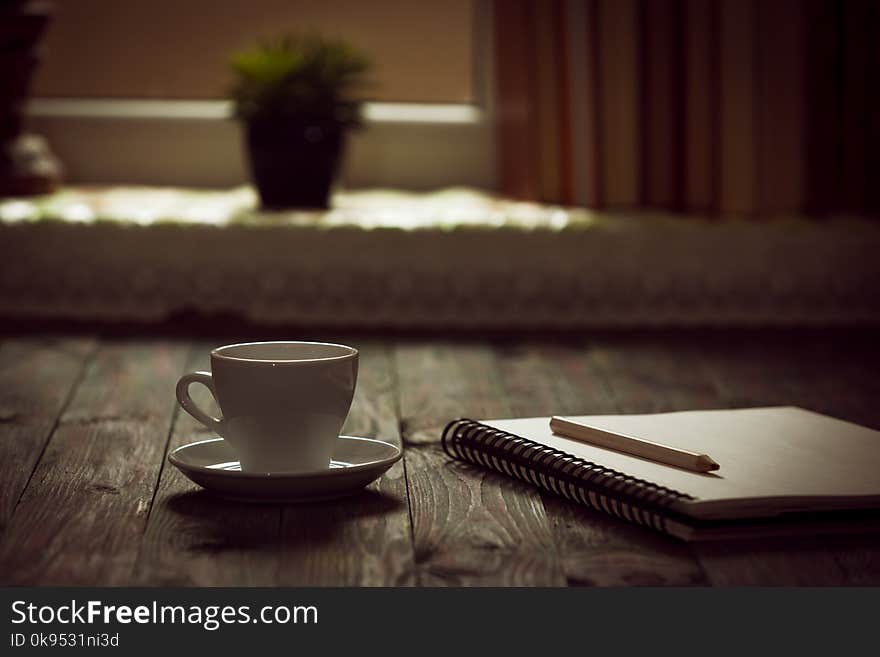 A cup of coffee in the workplace on a wooden table.