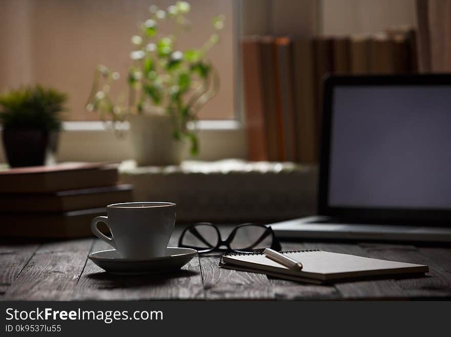 A cup of coffee in the workplace on a wooden table.