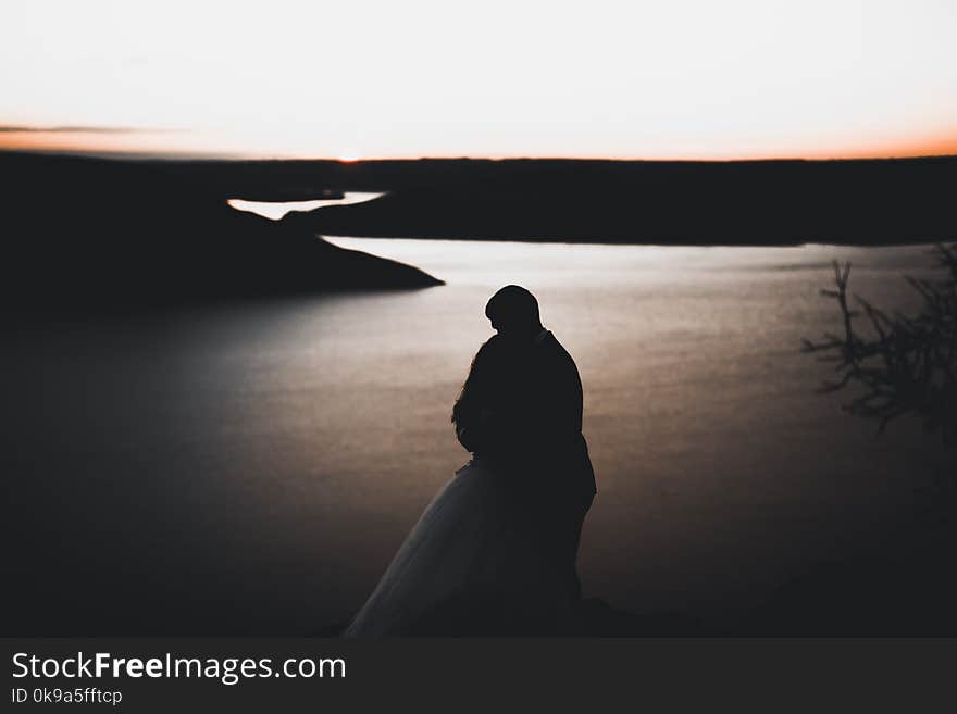 Wedding couple, groom, bride posing near sea on sunset