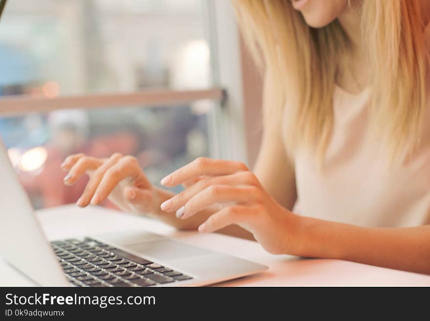 A young girl, female hands are printing on a laptop in a cafe , business woman