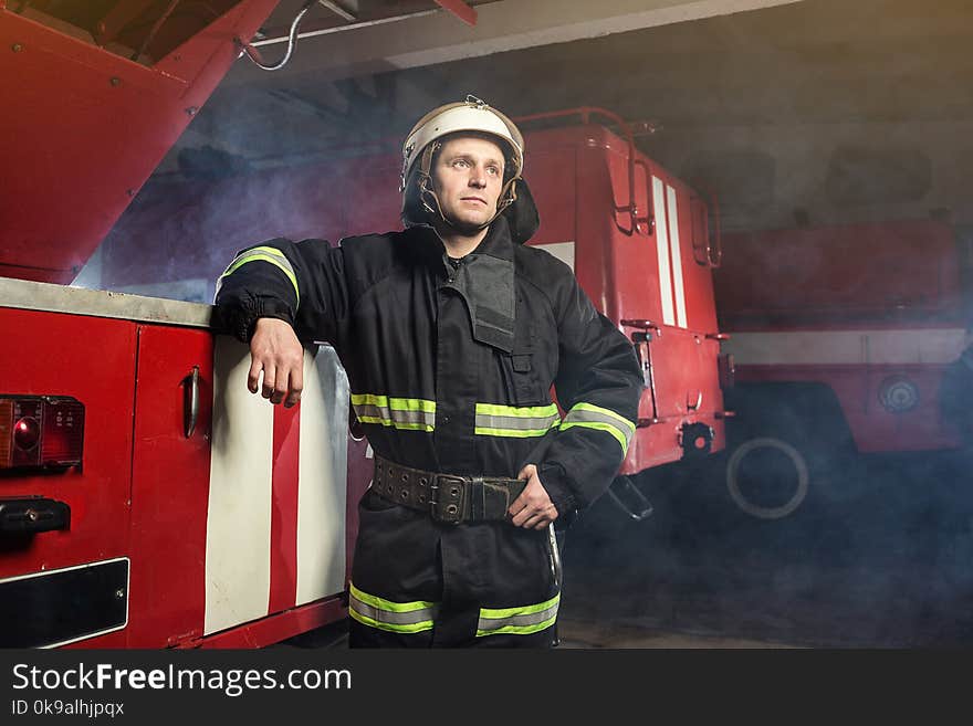 Fireman firefighter in action standing near a firetruck. Emergency safety. Protection, rescue from danger.