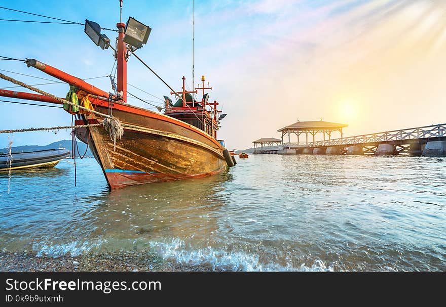 fishing boat on a beach with white wooden bridge at sunrise