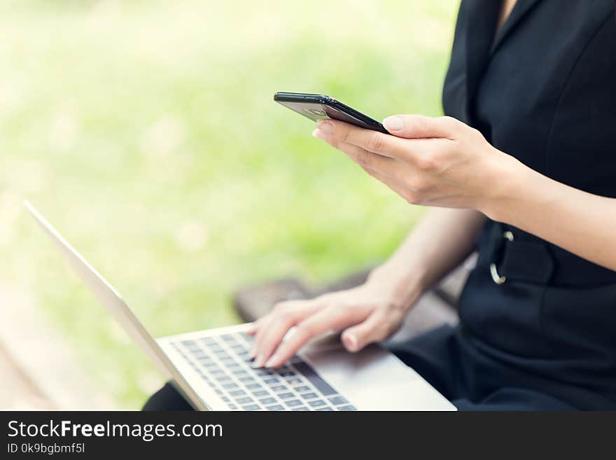 Business women using laptop and smartphone to working her job in the park outdoor