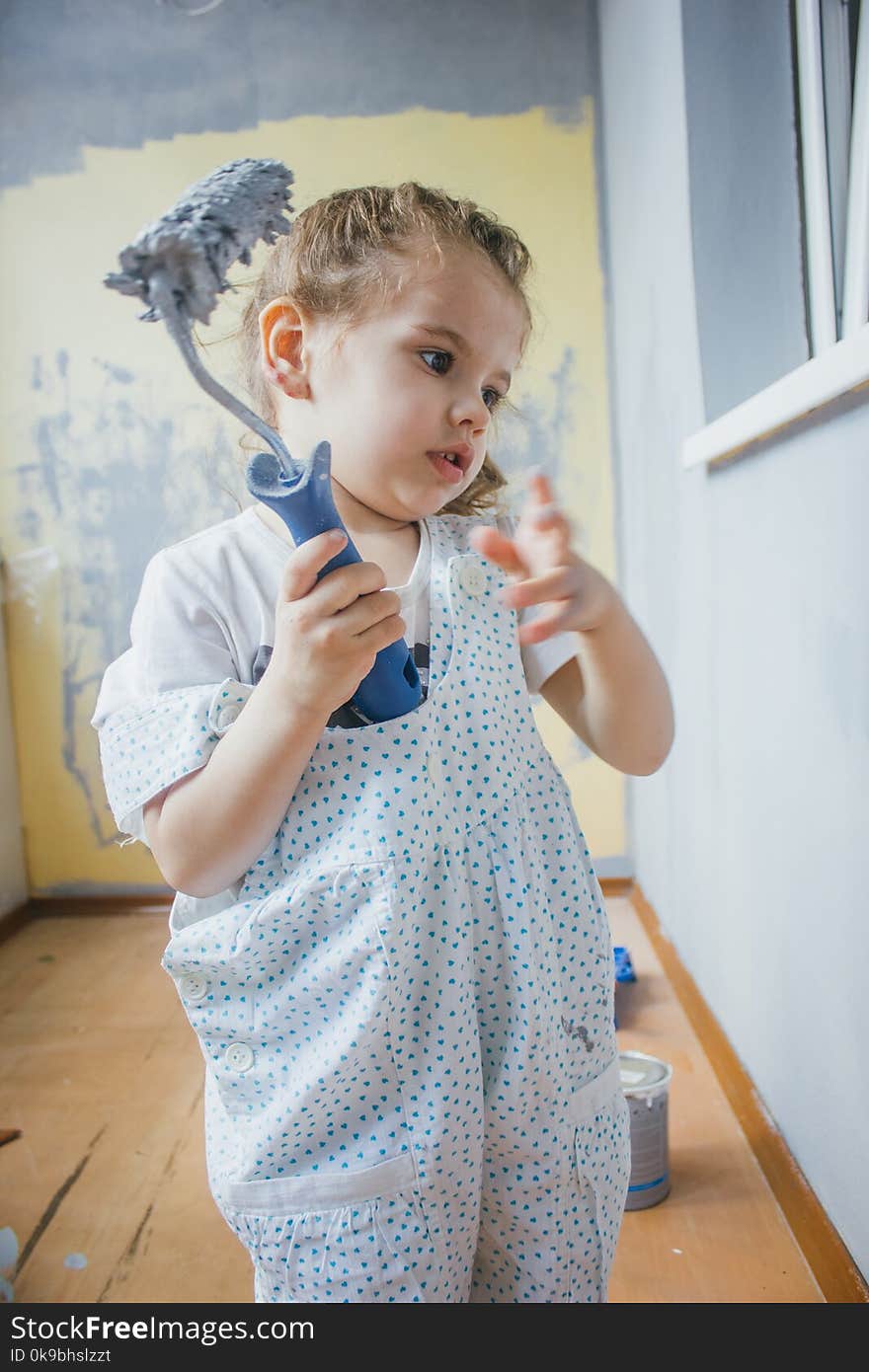 Little Girl Holding Paint Roller By Hands At Room.