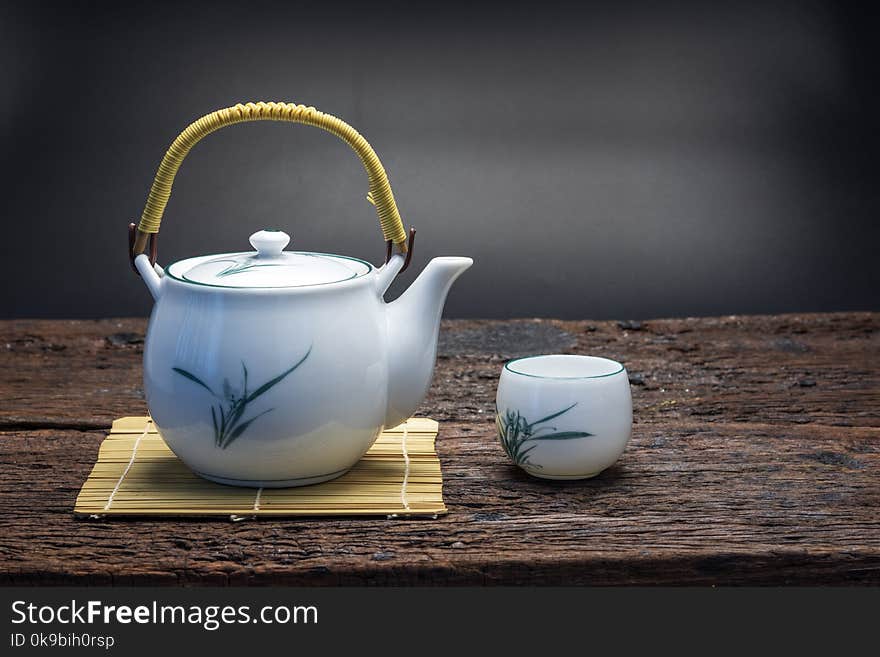 Hot tea pot on bamboo mat with cup on wooden table, chinese or japanese lifestyle