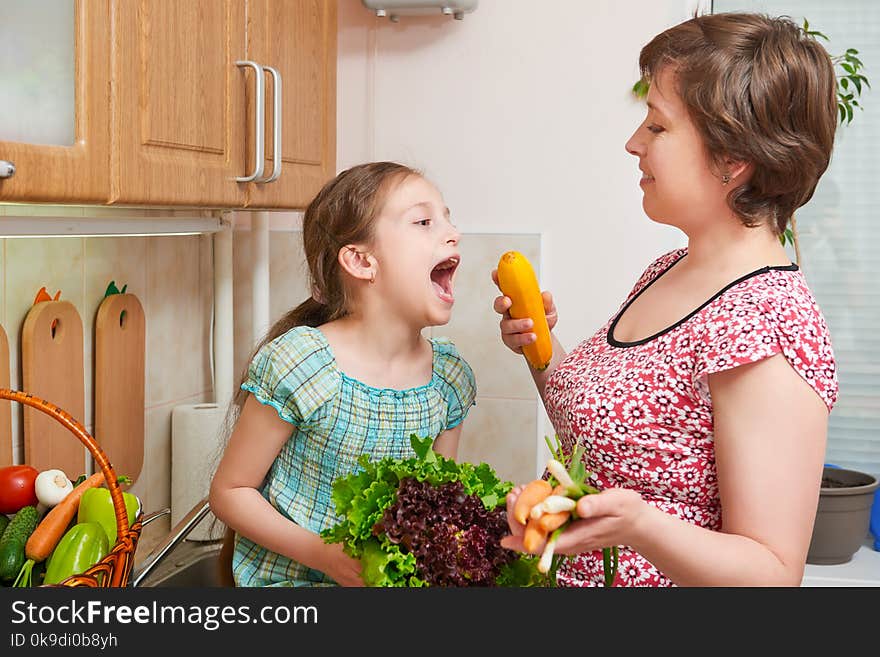 Mother and daughter with basket of vegetables and fresh fruits in home kitchen interior - healthy food concept