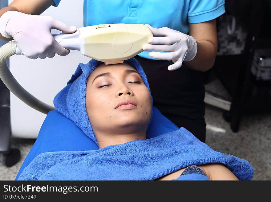 Treatment on Asian Woman as patient to make skin smooth bright and cure acne with medical beauty device instrument cold process on face in hospital clinic with acne wart. Treatment on Asian Woman as patient to make skin smooth bright and cure acne with medical beauty device instrument cold process on face in hospital clinic with acne wart
