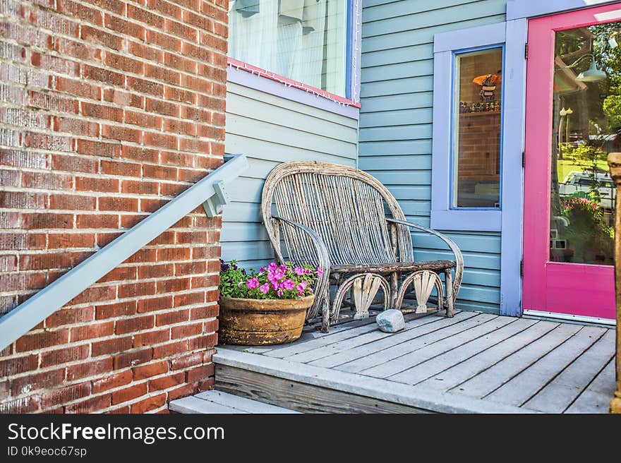 An inviting back porch entrance with a bench and pot of pink petunia flowers. An inviting back porch entrance with a bench and pot of pink petunia flowers.