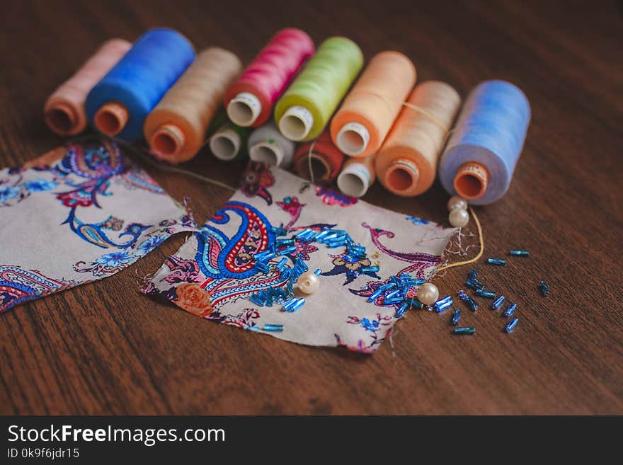 scraps of fabric with beads and colorful threads on a wooden background. scraps of fabric with beads and colorful threads on a wooden background