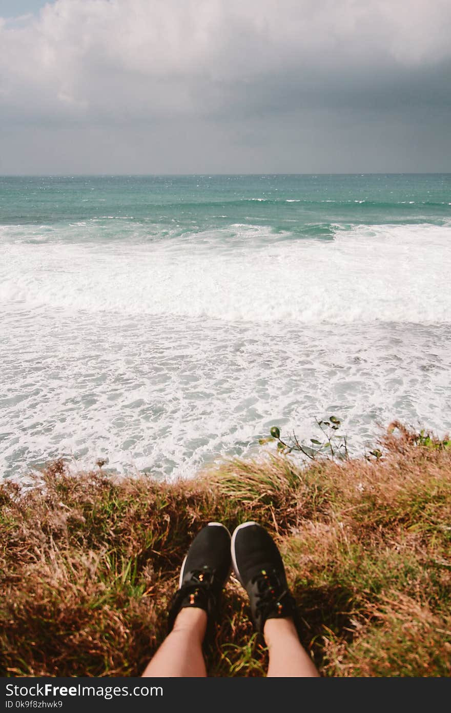 Person Wearing Pair of Black Running Shoes Near Body of Water