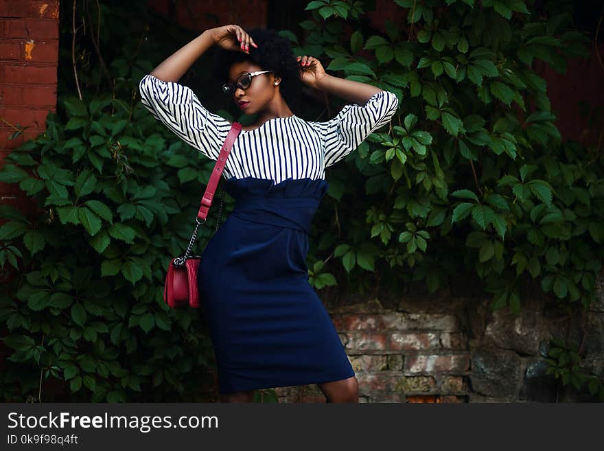 Woman in Black and White Striped Long-sleeved Dress Wearing Red Leather Sling Bag