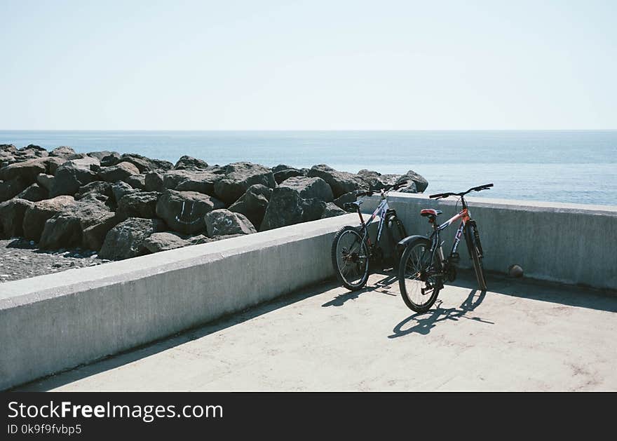 Two Bicycles Behind Gray Concrete Wall