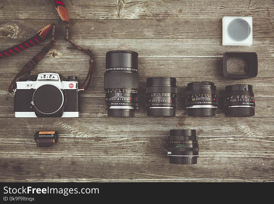 Black and Gray Dslr Camera With Assorted Lenses on Brown Wooden Surface