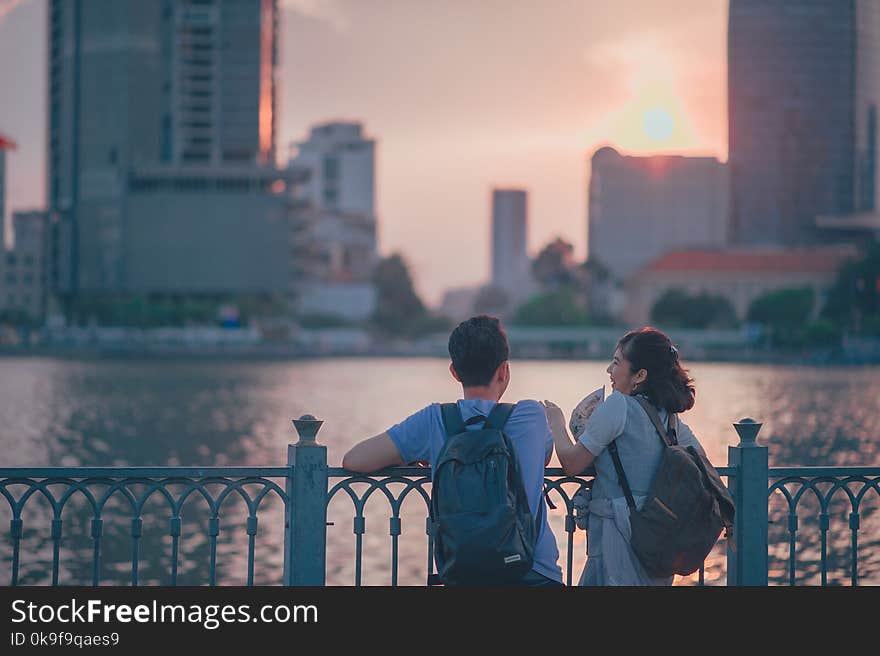 Couple Having Conversion Near Metal Fence during Golden Hour