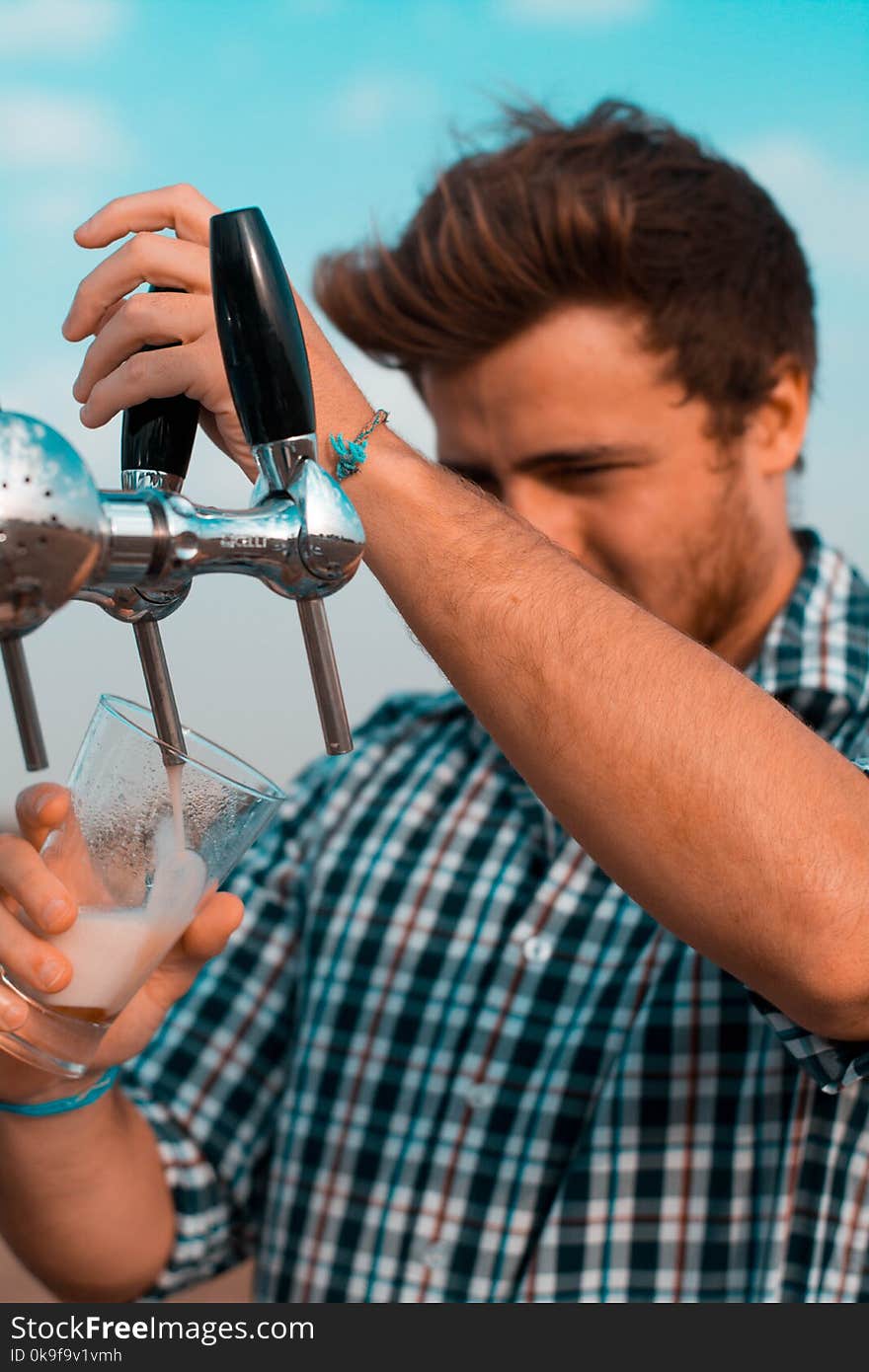 Man Holding Black Beer Tap Handle Pouring Beer on Clear Glass