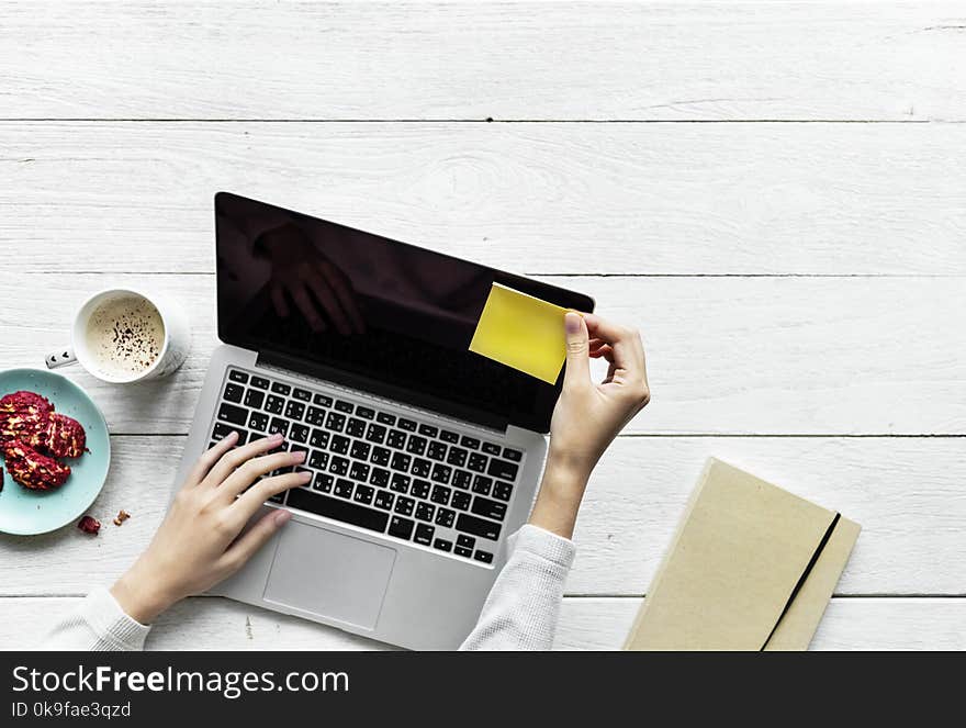 Person Holding Black And Grey Laptop Computer On Top Of White Wood Surface