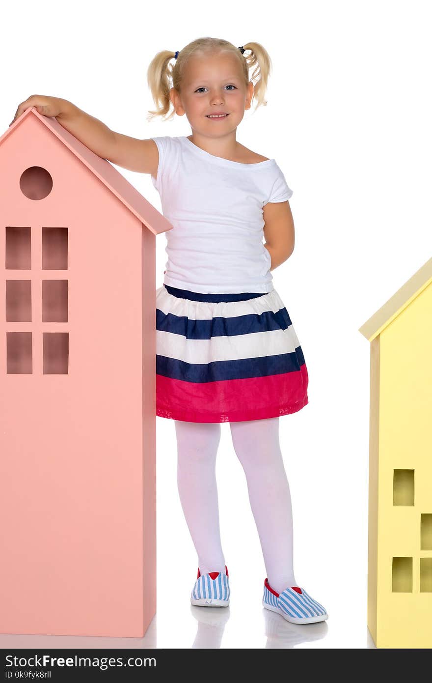 A cute little girl is playing with wooden houses. The concept of family happiness, play, creative development of the child.