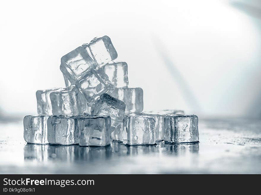 Ice cube on wooden table and light blurred background