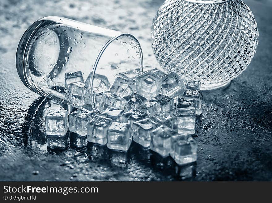 Glass of Ice cube on wooden table and light blurred background