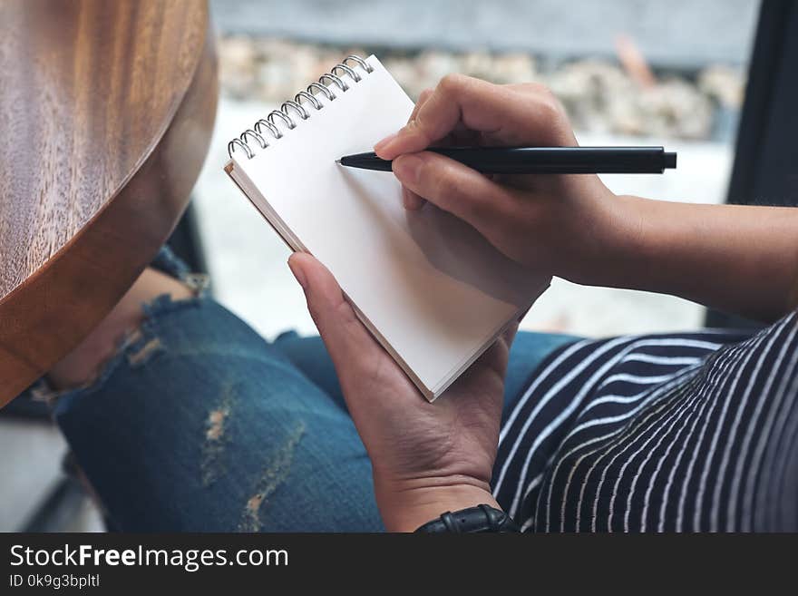 Closeup image of a woman`s hands writing down on a white blank notebook. Closeup image of a woman`s hands writing down on a white blank notebook