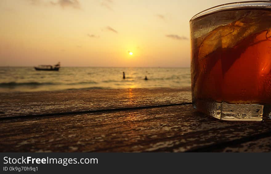 close up of a cocktail in front of tropical sunset. close up of a cocktail in front of tropical sunset