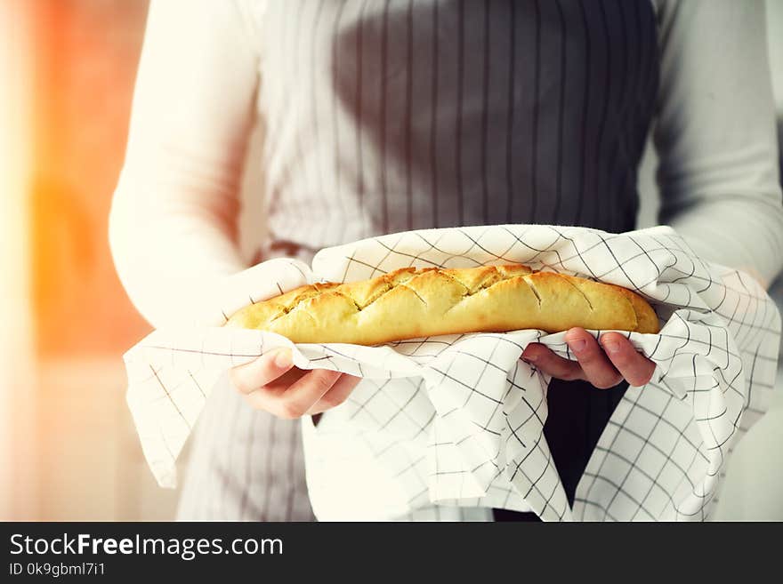 Woman hands holding freshly baked bread. French baguette, bakery concept, homemade food, healthy eating. Copy space