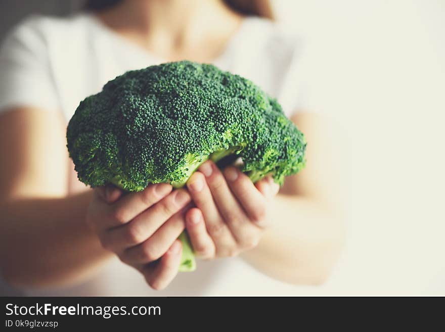 Woman in white T-shirt holding broccoli in hands. Copy space. Healthy clean detox eating concept. Vegetarian, vegan, raw concept.