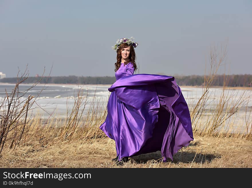 Woman lilac dress with a wreath of flowers on her head on nature