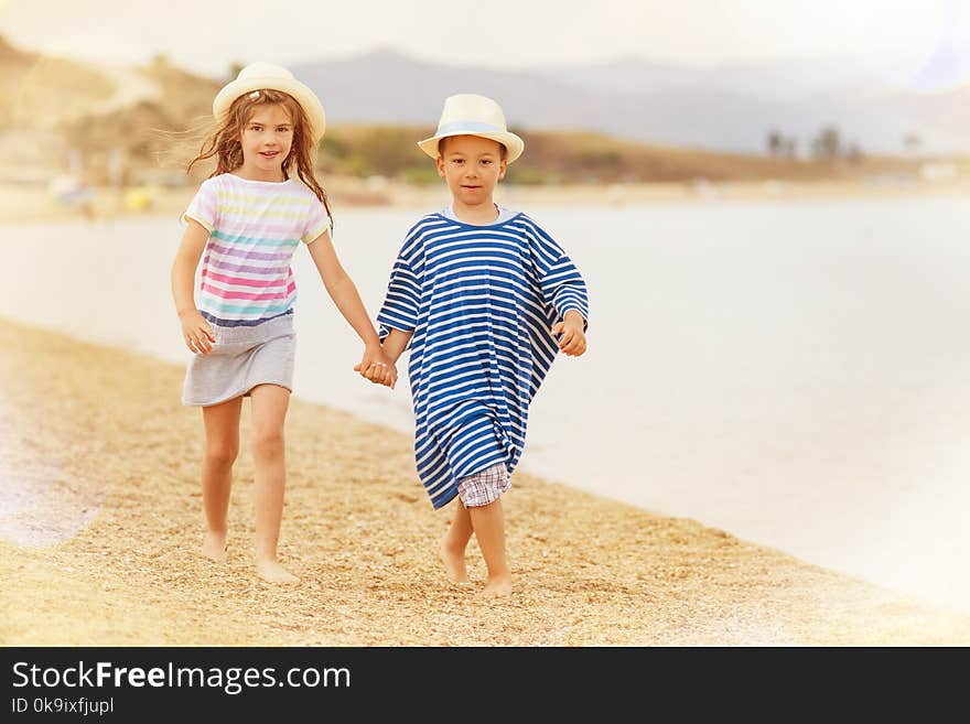 A boy and a girl around six holding hands while taking a walk on the beach smiling. A boy and a girl around six holding hands while taking a walk on the beach smiling.