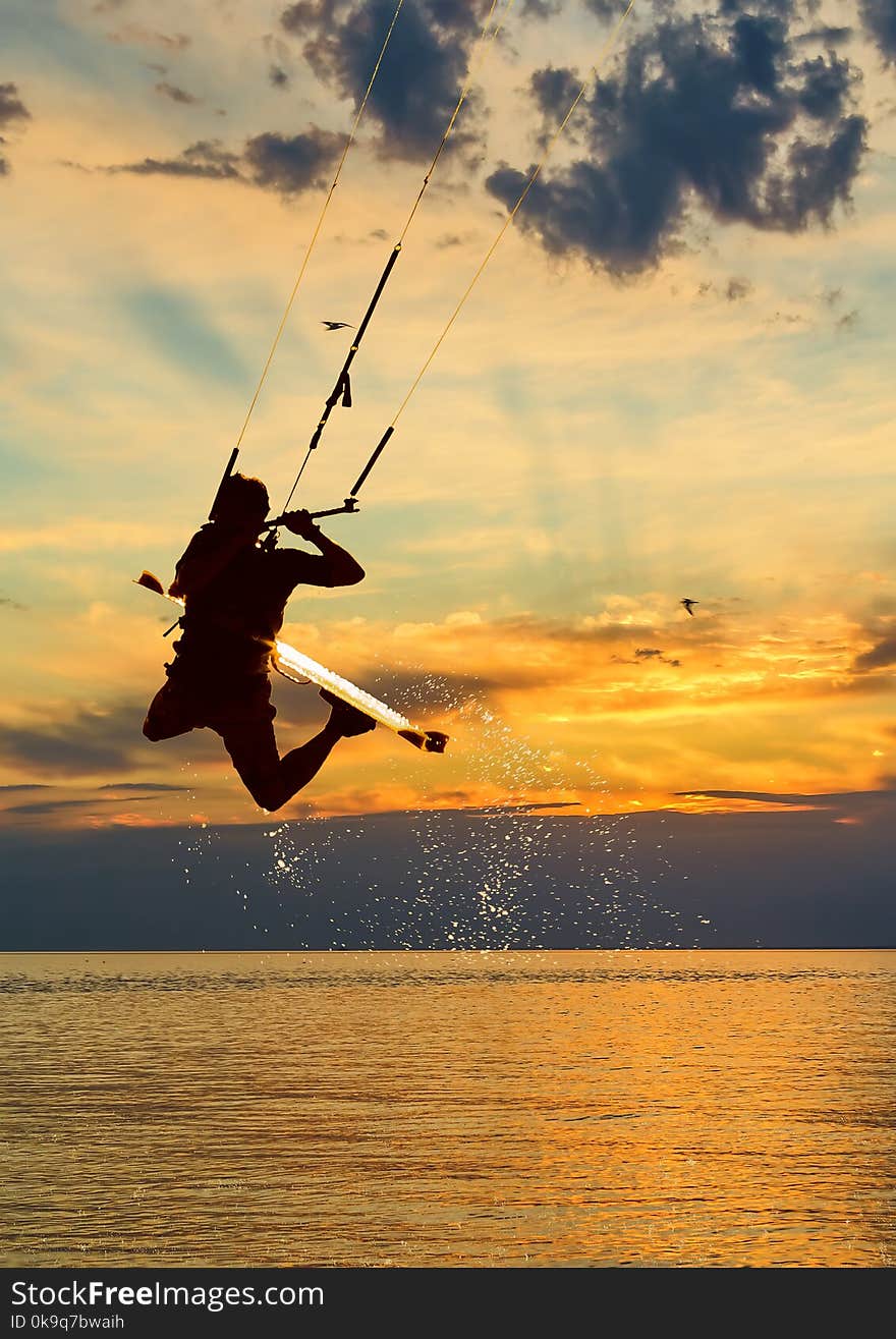 Silhouette of kitesurfer on sunset sky background