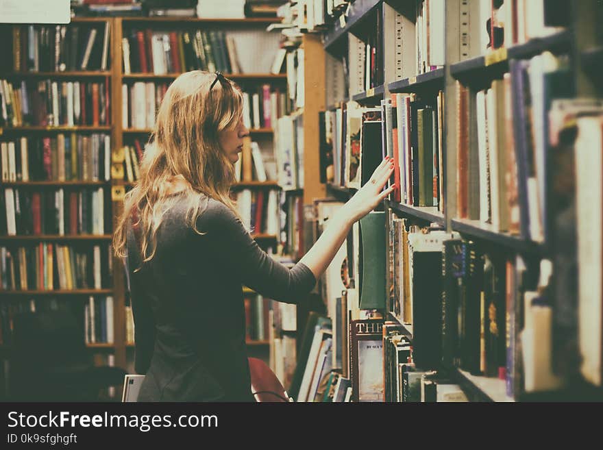 Woman in Black Long-sleeved Looking for Books in Library